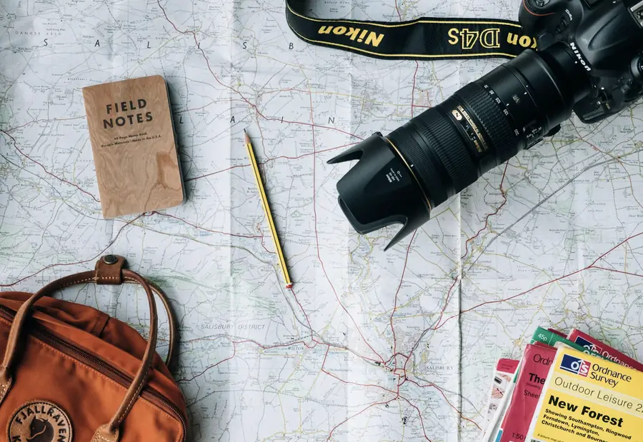 Mapa desplegado con cuaderno de notas, cámara y mochila de viaje